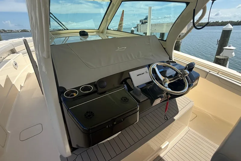  Yacht Photos Pics 2022 Scout 425 LXF boat helm with steering wheel and controls, docked by the water.