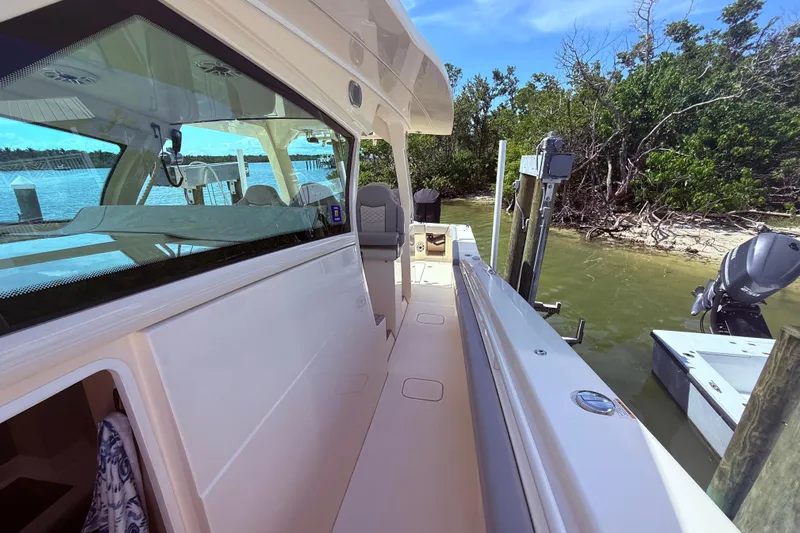  Yacht Photos Pics 2022 Scout 425 LXF boat docked by a scenic shoreline with lush greenery.