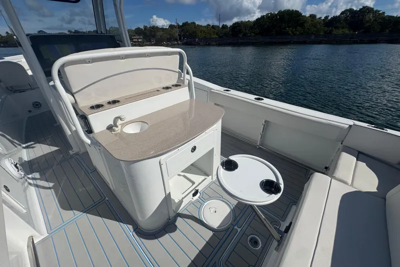  Yacht Photos Pics 2023 Sea Hunt Ultra 305 SE boat interior with seating, table, and sink by the water.