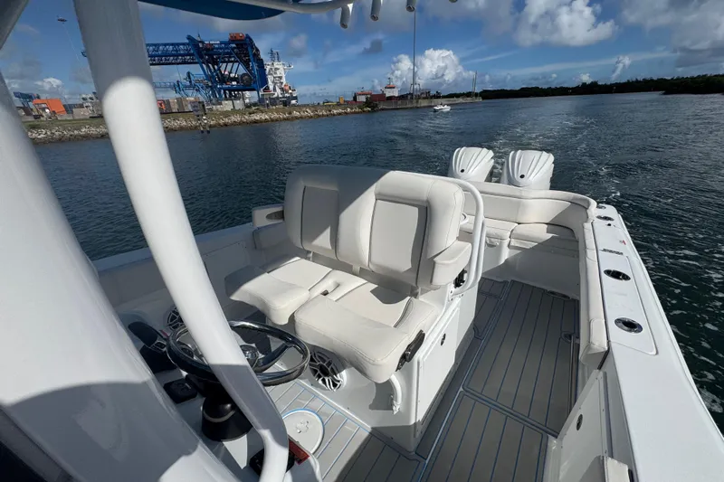  Yacht Photos Pics 2023 Sea Hunt Ultra 305 SE boat interior with white seating, steering wheel, and ocean backdrop.