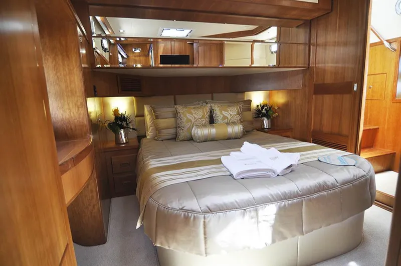  Yacht Photos Pics Luxurious bedroom interior of 2026 Alaska 47 Flybridge yacht with elegant bedding and wood finishes.