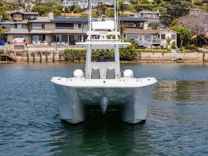  Yacht Photos Pics 2024 Invincible 35 Catamaran on water, with waterfront homes in the background.