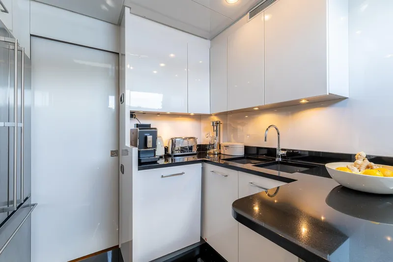 Easy Yacht Photos Pics Modern kitchen interior on 2009 Sanlorenzo 82 yacht with sleek white cabinets and black countertops.