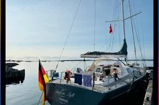 Sinfonie Sylt Yacht Photos Pics Grand Soleil 70 yacht, 2001 model, docked with flags, calm waters in the background.