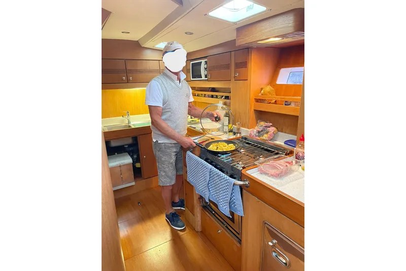 Sinfonie Sylt Yacht Photos Pics Man cooking in the kitchen of a 2001 Grand Soleil 70 yacht.