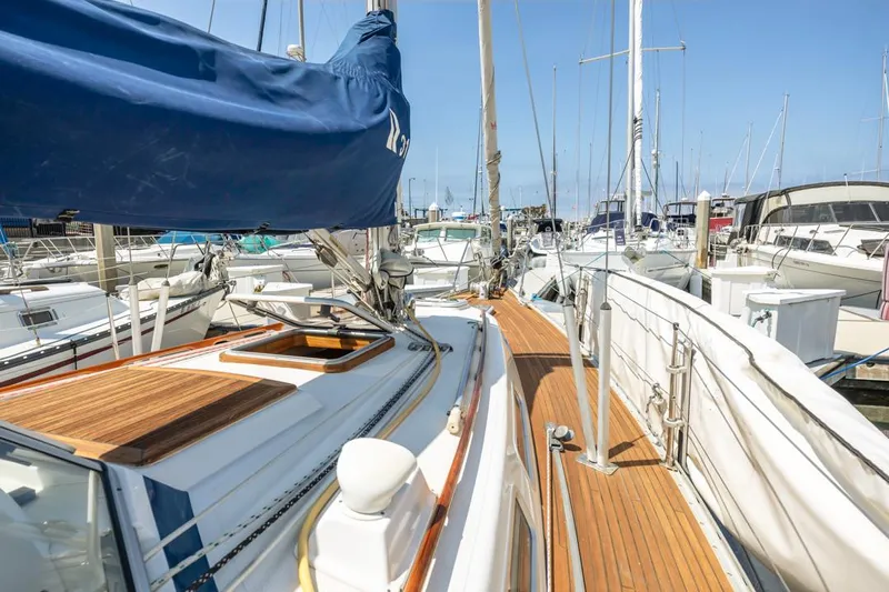 Roniin Yacht Photos Pics 2003 Hallberg-Rassy HR31 sailboat docked in marina, showcasing teak deck and blue sail cover.