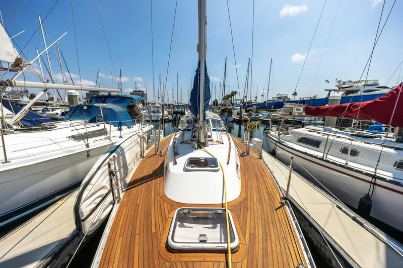 Roniin Yacht Photos Pics 2003 Hallberg-Rassy HR31 sailboat docked in a marina, showcasing teak deck and clear blue sky.