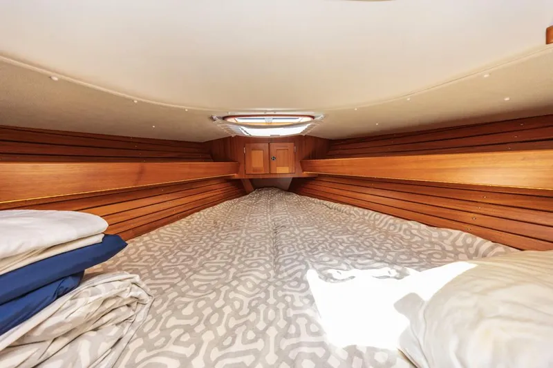 Roniin Yacht Photos Pics Cozy cabin interior of 2003 Hallberg-Rassy HR31 sailboat with wooden paneling and bedding.