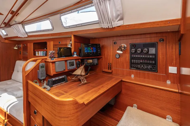 Roniin Yacht Photos Pics Interior of 2003 Hallberg-Rassy HR31 sailboat with navigation equipment and wooden finish.