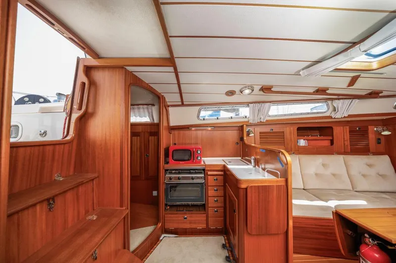 Roniin Yacht Photos Pics Interior of 2003 Hallberg-Rassy HR31 yacht with wood finish, kitchen, and seating area.
