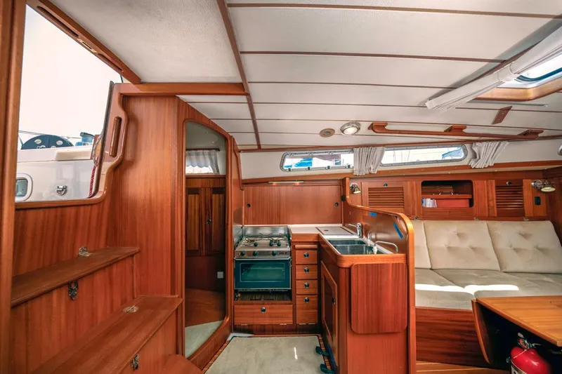 Roniin Yacht Photos Pics Interior of 2003 Hallberg-Rassy HR31 yacht with wooden cabinetry and cozy seating area.