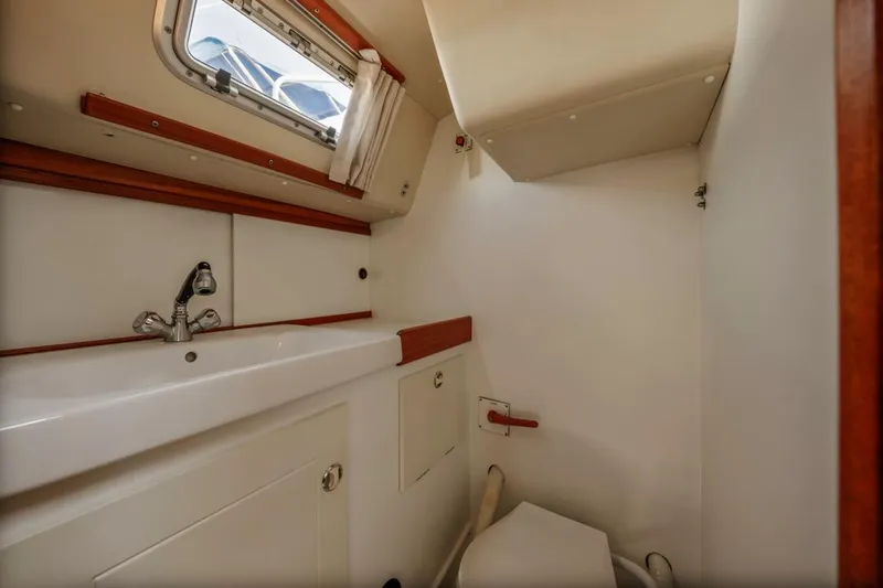 Roniin Yacht Photos Pics Compact bathroom in 2003 Hallberg-Rassy HR31 yacht with sink, faucet, and window.