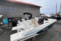 2026 Quicksilver 705 Open boat displayed at a marina with wooden siding.