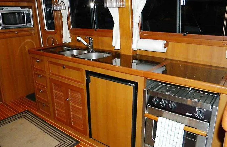 Kairos Yacht Photos Pics 2005 Selene 36 yacht kitchen with wooden cabinetry, sink, stove, and refrigerator.