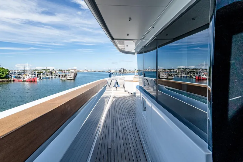 Neverland Yacht Photos Pics Sanlorenzo 44 Alloy 2020 yacht deck with marina view, clear skies, and wooden railings.