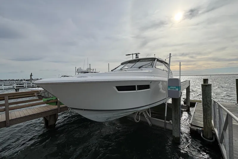 Yacht Photos Pics 2022 Pursuit DC 365 Dual Console boat docked on a lift at a marina.