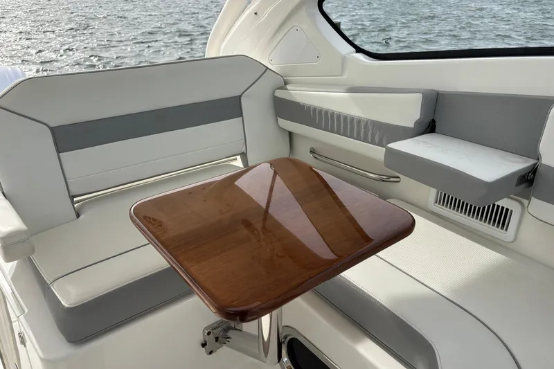  Yacht Photos Pics 2022 Pursuit DC 365 Dual Console interior with seating and wooden table by the water.