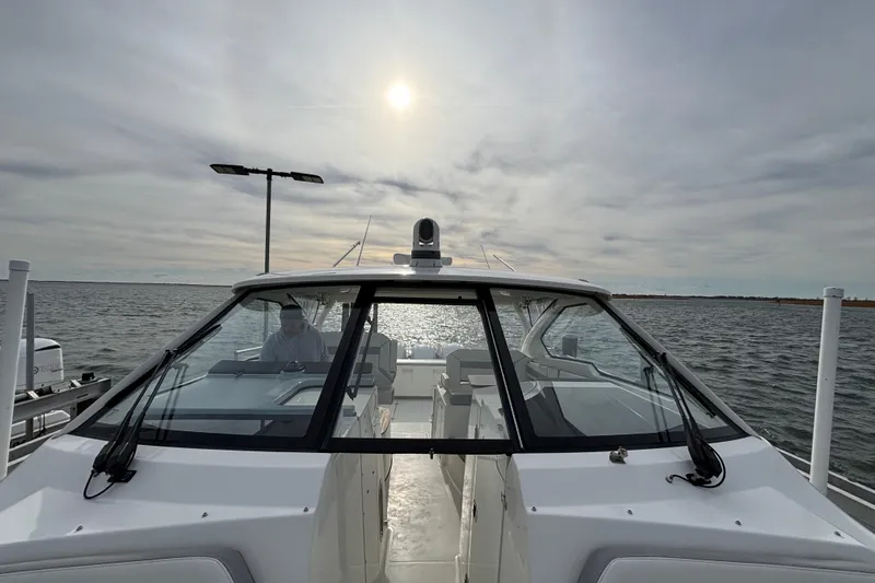  Yacht Photos Pics 2022 Pursuit DC 365 Dual Console boat on water under cloudy sky.