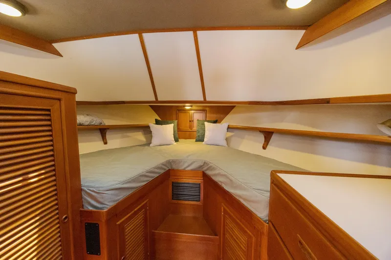  Yacht Photos Pics 1989 Offshore Yachts 48 Yachtfisher cabin interior with cozy bed and wooden furnishings.