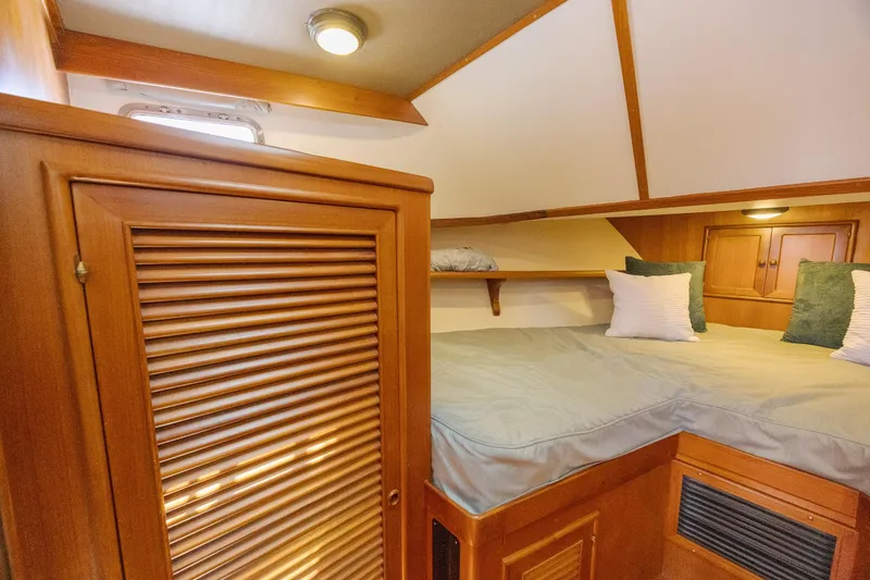  Yacht Photos Pics 1989 Offshore Yachts 48 Yachtfisher cabin with wooden interior and cozy bedding.