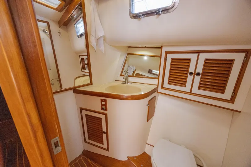  Yacht Photos Pics 1989 Offshore Yachts 48 Yachtfisher bathroom with sink, mirror, and wooden cabinets.