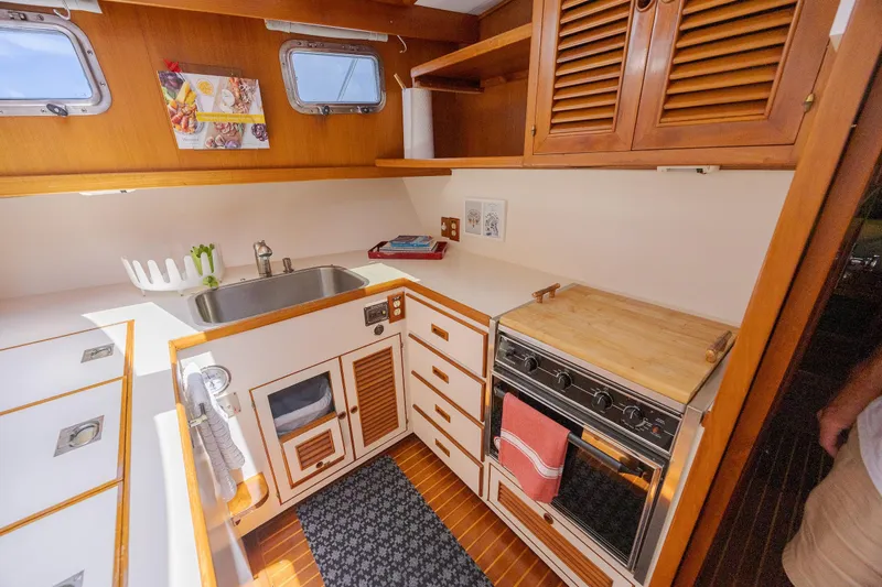  Yacht Photos Pics 1989 Offshore Yachts 48 Yachtfisher kitchen with wooden cabinets, stove, and sink.
