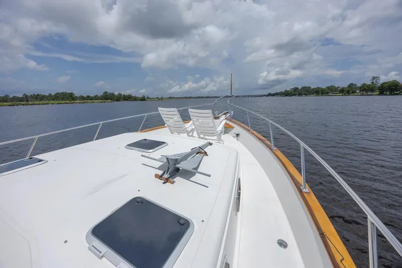  Yacht Photos Pics 1989 Offshore Yachts 48 Yachtfisher cruising on a calm river under a cloudy sky.
