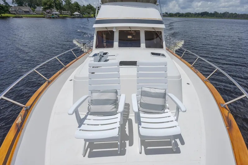  Yacht Photos Pics 1989 Offshore Yachts 48 Yachtfisher with deck chairs cruising on a serene waterway.