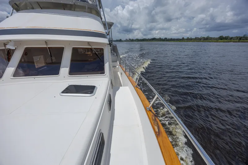  Yacht Photos Pics 1989 Offshore Yachts 48 Yachtfisher cruising on a calm river under cloudy skies.