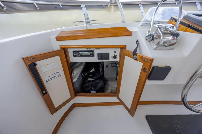  Yacht Photos Pics 1989 Offshore Yachts 48 Yachtfisher cockpit storage with open wooden cabinet and control panel.