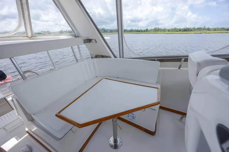  Yacht Photos Pics 1989 Offshore Yachts 48 Yachtfisher interior with white seating and table, overlooking serene water.
