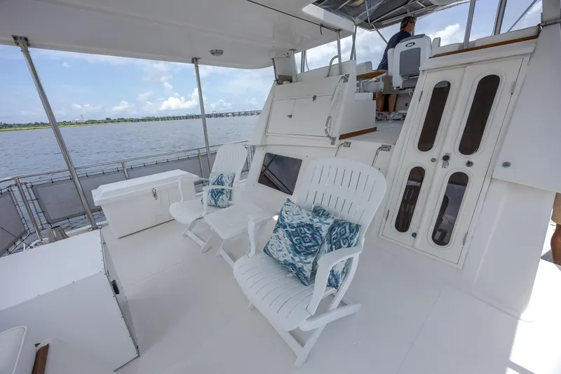  Yacht Photos Pics 1989 Offshore Yachts 48 Yachtfisher deck with white chairs and blue cushions, overlooking water.