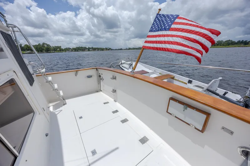  Yacht Photos Pics 1989 Offshore Yachts 48 Yachtfisher deck with American flag, cruising on a scenic waterway.