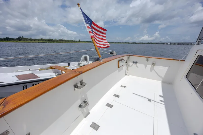  Yacht Photos Pics 1989 Offshore Yachts 48 Yachtfisher deck with American flag, cruising on a calm river.