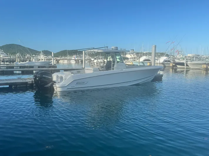  Yacht Photos Pics 2017 Boston Whaler 330 Outrage boat docked in a marina with clear blue water.