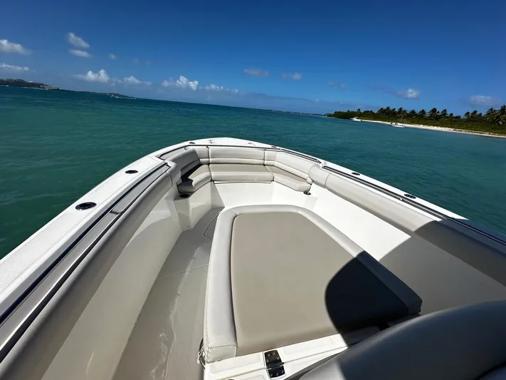  Yacht Photos Pics 2017 Boston Whaler 330 Outrage boat on clear blue water near a tropical shoreline.