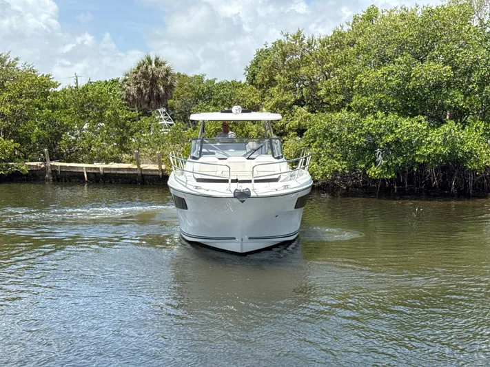  Yacht Photos Pics 2022 Jeanneau Leader 10.5 WA Series 2 cruising on a calm waterway surrounded by greenery.