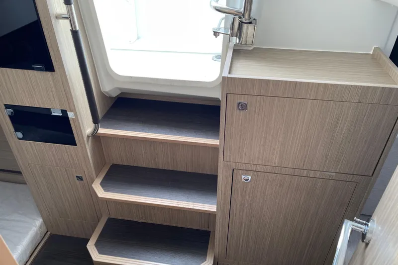  Yacht Photos Pics 2024 Jeanneau Leader 10.5 CC interior stairs with wood finish and storage cabinets.