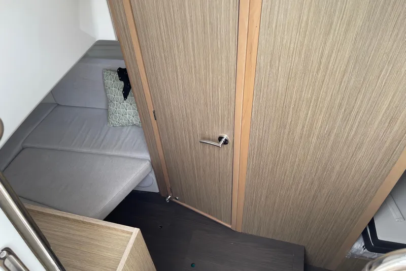  Yacht Photos Pics 2024 Jeanneau Leader 10.5 CC cabin interior with wooden door and cushioned seating.