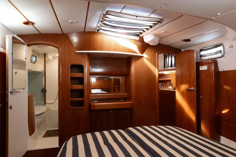 Yacht Photos Pics 1999 Beneteau Oceanis 44 CC yacht interior with wood finish and striped bedding.