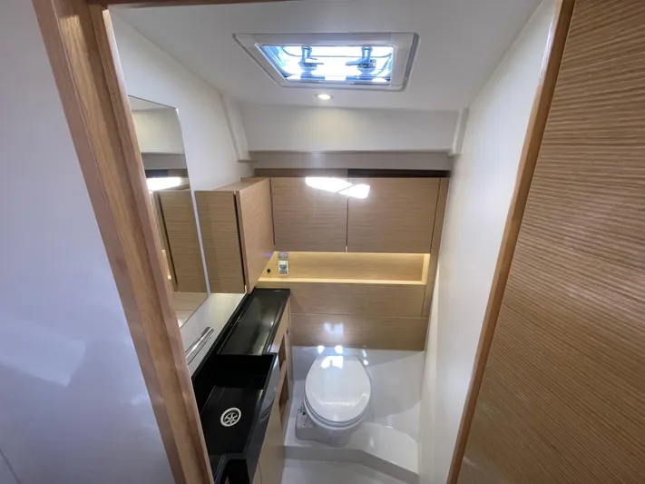 In Stock Yacht Photos Pics Modern bathroom interior of 2024 Hanse 410 yacht with wood accents and skylight.