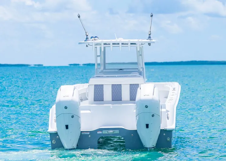  Yacht Photos Pics 2026 Invincible 33 Catamaran on clear blue ocean water, rear view.