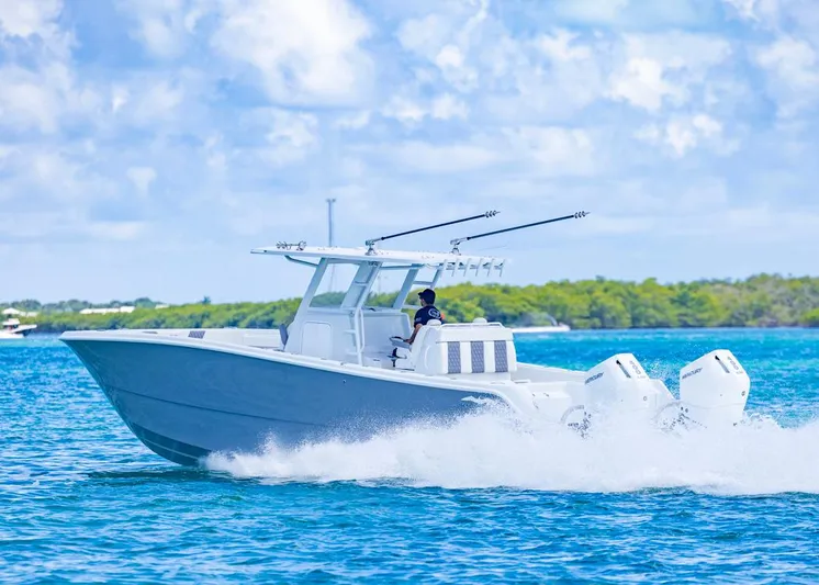  Yacht Photos Pics 2026 Invincible 33 Catamaran cruising on blue water with lush green background.