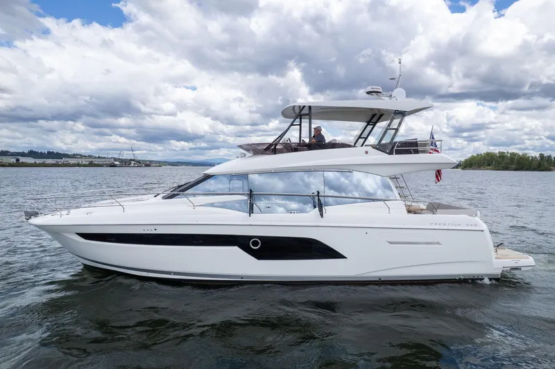  Yacht Photos Pics 2022 Prestige 520 yacht cruising on a calm lake under a cloudy sky.