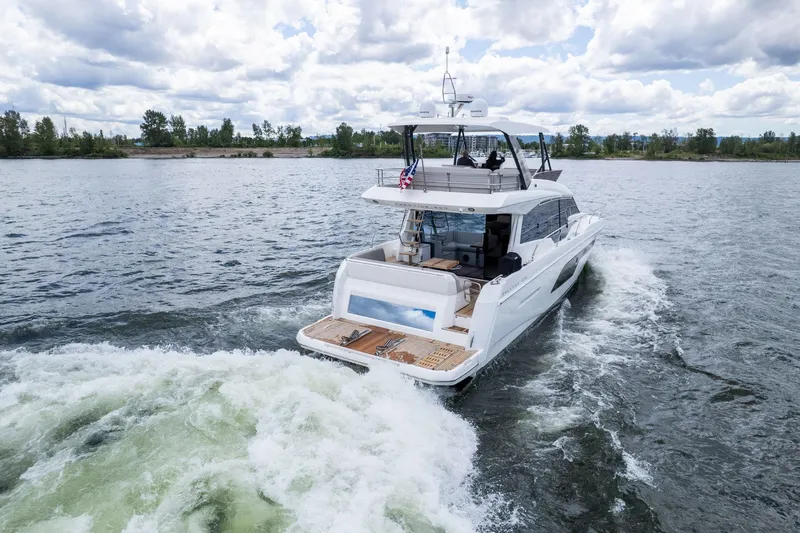  Yacht Photos Pics 2022 Prestige 520 yacht cruising on a scenic lake under a cloudy sky.