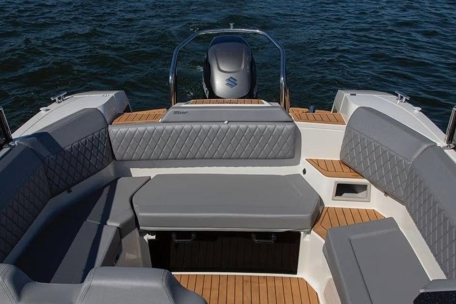 2023 Silver Raptor DCz boat interior with cushioned seating and wooden flooring on water.