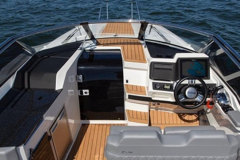 2023 Silver Raptor DCz boat interior with modern dashboard and wooden flooring on water.