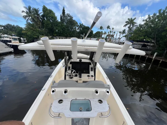  Yacht Photos Pics 2025 Scout 261 XSS boat with fishing rod holders, docked on a calm waterway.