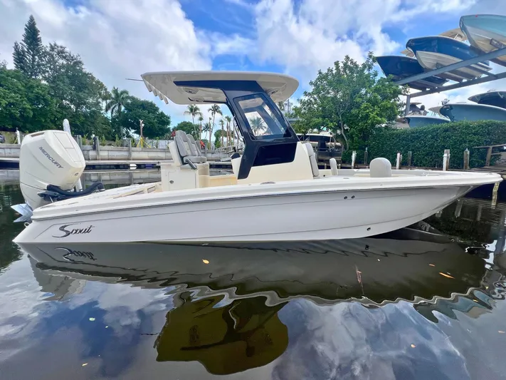  Yacht Photos Pics 2025 Scout 261 XSS boat docked on calm water, surrounded by lush greenery and clear skies.
