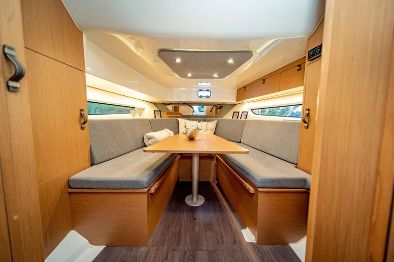  Yacht Photos Pics 2024 Beneteau Flyer 10 cabin interior with cozy seating and wooden table.